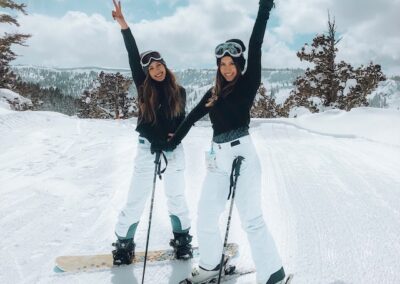 two cheerful women standing in the snow with skiis